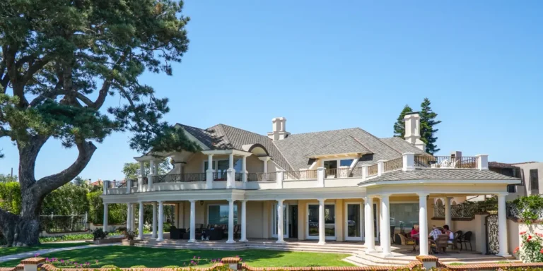 Large home with columns and a landscaped lawn