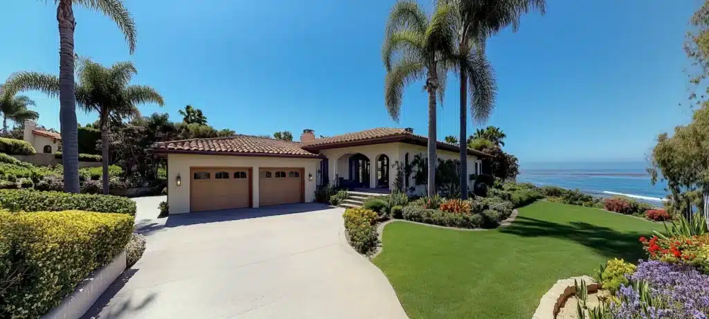 A single-story Mediterranean home with a long driveway and a wide lawn