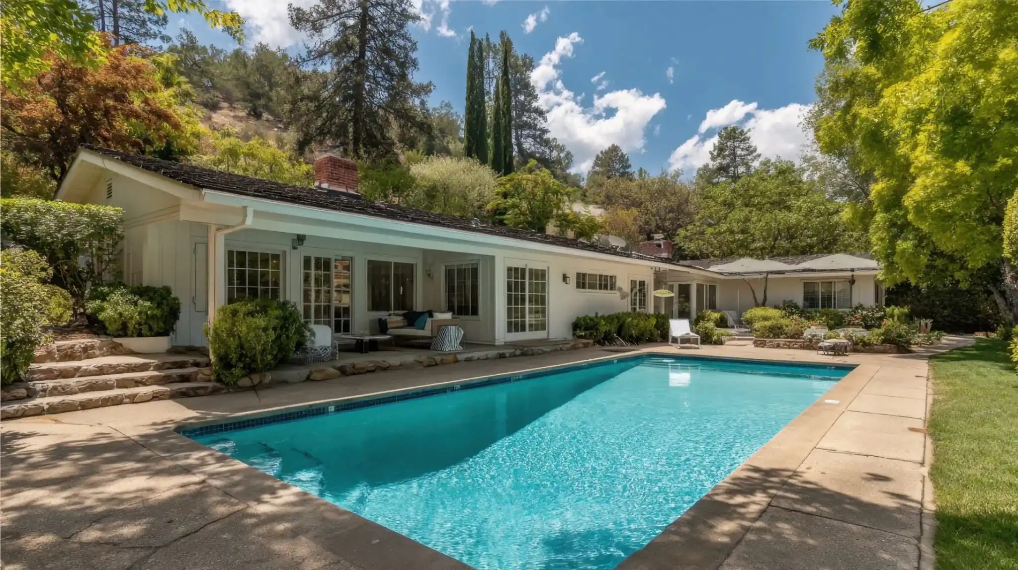 Single-story ranch home with a pool and mature trees
