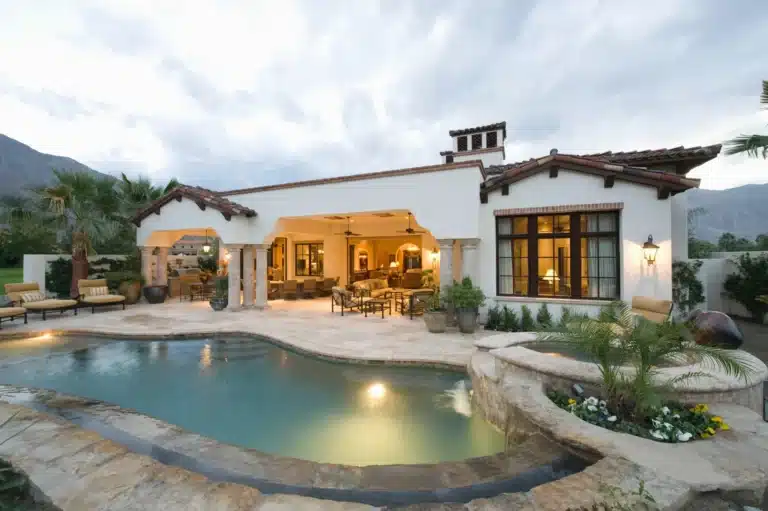 Spanish-style home with a patio and pool at sunset